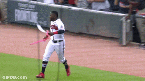 A Baseball Player Is Holding A Pink Ribbon On A Baseball Field GIF
