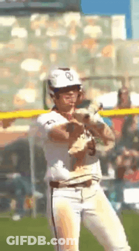 A Baseball Player Is Holding A Small Dog In His Hand GIF