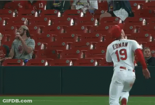 A Baseball Player Is Laying On The Field While A Fan Watches . GIF