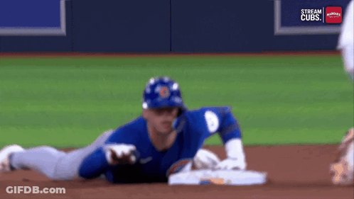 A Baseball Player Is Laying On The Ground On The Field . GIF