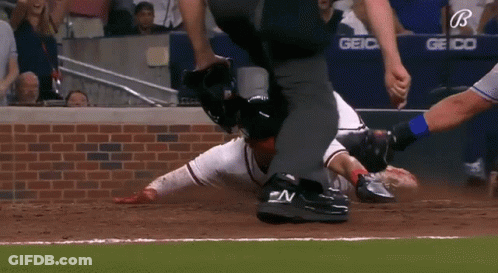 A Baseball Player Is Laying On The Ground While A Referee Watches GIF
