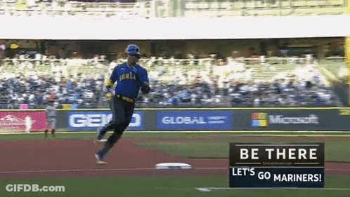 A Baseball Player Is Running On A Field With A Sign That Says Let 'S Go Mariners GIF