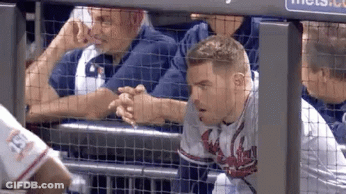 A Baseball Player Is Shaking Hands With A Fan While Sitting In The Dugout . GIF