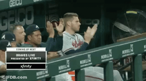 A Baseball Player Is Sitting In The Dugout Applauding His Team . GIF