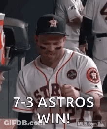 A Baseball Player Is Sitting In The Dugout With His Fist In The Air And Says `` 7- 3 Astros Win '' . GIF