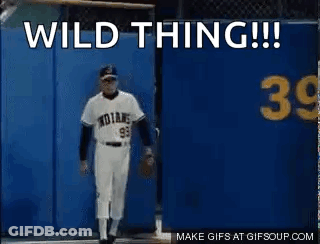A Baseball Player Is Standing In Front Of A Blue Wall With The Words `` Wild Thing '' Written On It . GIF