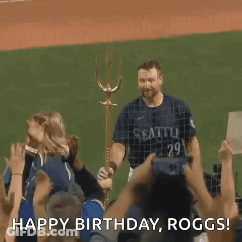 A Baseball Player Is Standing In Front Of A Crowd Holding A Trident And Saying Happy Birthday Roggs . GIF
