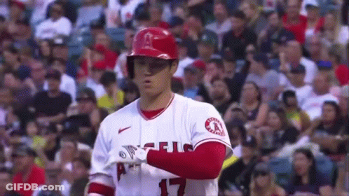 A Baseball Player Is Standing In Front Of A Crowd While Wearing A Helmet . GIF