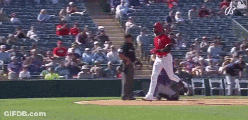 A Baseball Player Is Standing On A Baseball Field With A Referee Standing Behind Him . GIF
