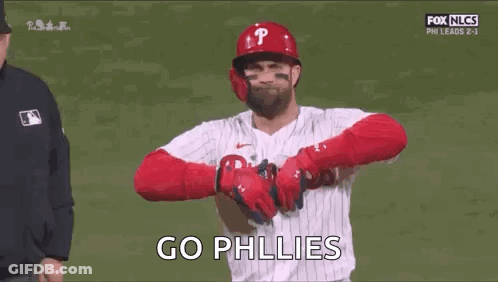 A Baseball Player Is Standing On A Field With His Arms Crossed And A Referee Behind Him . GIF