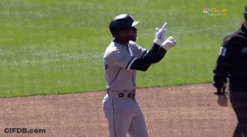 A Baseball Player Is Standing On A Field With His Arms In The Air . GIF