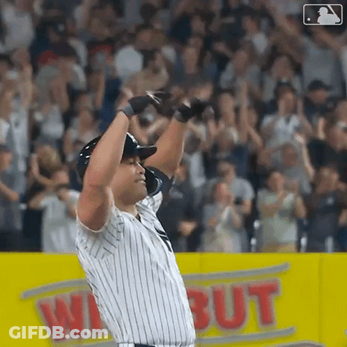 A Baseball Player Is Standing On The Field With His Arms In The Air GIF