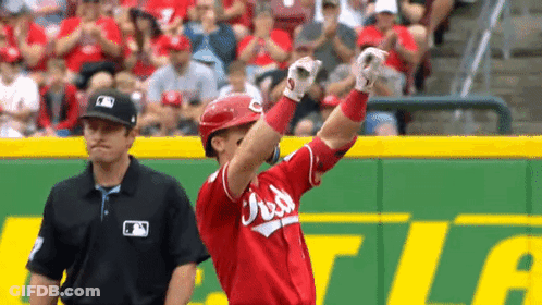 A Baseball Player Is Standing On The Field With His Arms In The Air While A Referee Watches . GIF