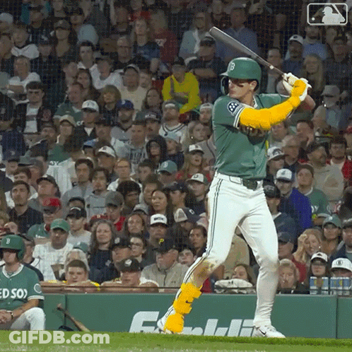 A Baseball Player Is Swinging A Bat In Front Of A Crowd With The Letter B On His Jersey GIF