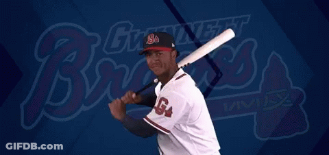 A Baseball Player Is Swinging A Bat In Front Of A Giant Night Brewers Logo GIF