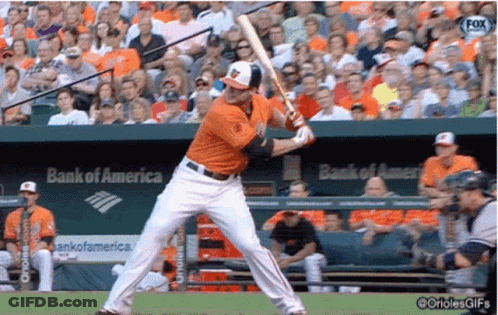 A Baseball Player Is Swinging At A Ball In Front Of A Bank Of America Sign GIF