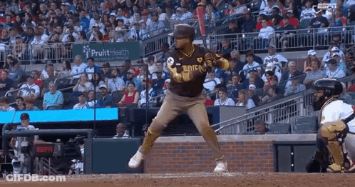 A Baseball Player Is Swinging At A Ball In Front Of A Crowd . GIF
