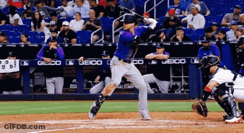 A Baseball Player Is Swinging At A Ball In Front Of A Geico Sign GIF
