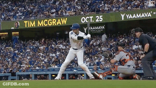 A Baseball Player Is Swinging At A Ball In Front Of A Sign That Says Tim Mcgraw GIF