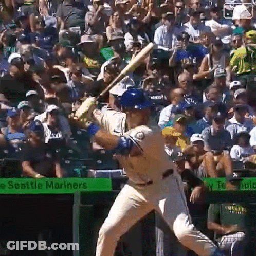 A Baseball Player Is Swinging At A Pitch In Front Of A Seattle Mariners Banner GIF
