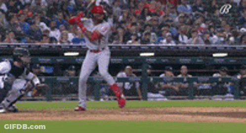 A Baseball Player Is Swinging His Bat At A Pitch During A Game GIF