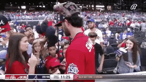 A Baseball Player Is Talking To A Woman In The Stands During A Game . GIF