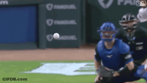 A Baseball Player Is Trying To Catch A Ball While A Catcher Is Kneeling On The Field . GIF