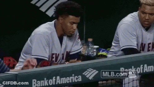 A Baseball Player Sits In The Dugout With A Bank Of America Ad Behind Him GIF