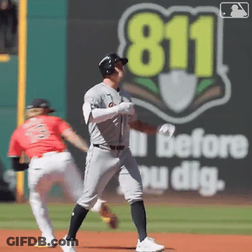 A Baseball Player Stands On The Field In Front Of A 911 Sign GIF