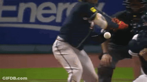 A Baseball Player Swings A Bat At A Ball While A Catcher Looks On GIF