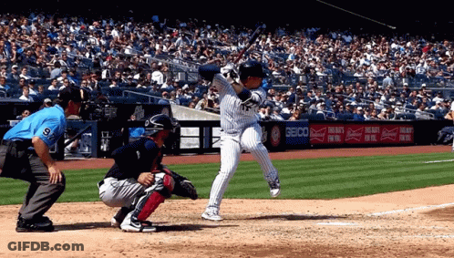 A Baseball Player Swings His Bat At A Pitch In Front Of A Seico Ad GIF