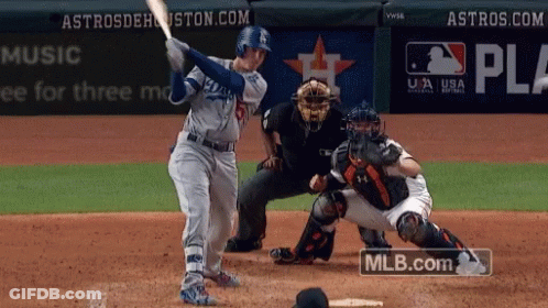 A Baseball Player Swings His Bat At A Pitch While A Catcher Watches GIF