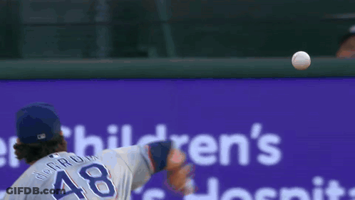 A Baseball Player Throws A Ball In Front Of A Sign That Says Children 'S Hospital GIF