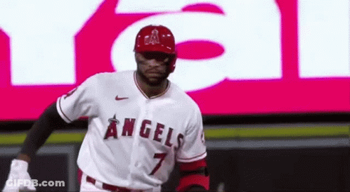 A Baseball Player Wearing A Angels Jersey Is Standing In Front Of A Large Screen . GIF