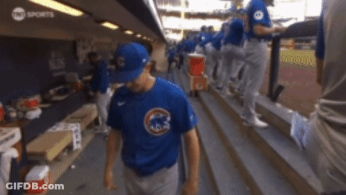 A Baseball Player Wearing A Blue Cubs Shirt Walks Down The Stairs GIF