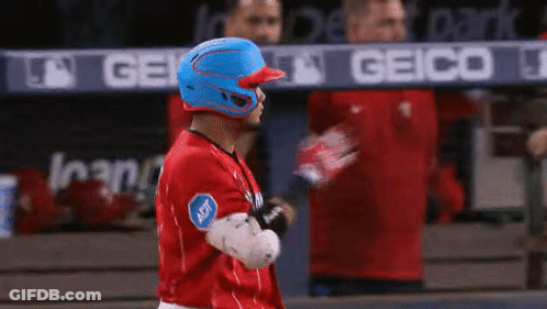 A Baseball Player Wearing A Blue Helmet Is Standing In Front Of A Geico Banner GIF