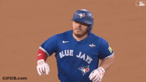 A Baseball Player Wearing A Blue Jays Uniform Is Running On The Field . GIF