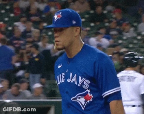 A Baseball Player Wearing A Blue Jays Uniform Is Standing In The Outfield . GIF