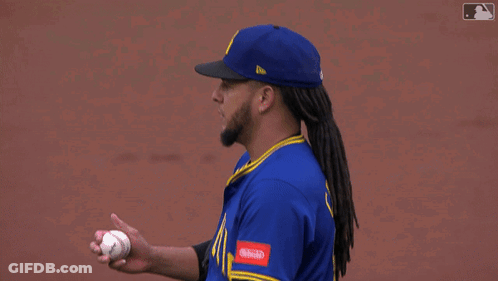 A Baseball Player Wearing A Blue Seattle Jersey Adjusts His Hat GIF