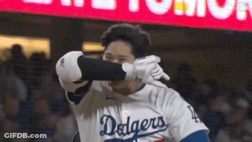 A Baseball Player Wearing A Dodgers Jersey Is Covering His Face With His Glove . GIF