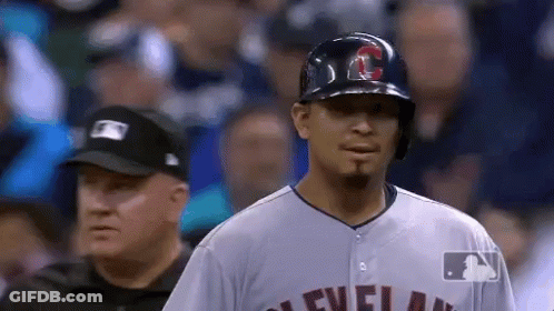 A Baseball Player Wearing A Helmet And A Cleveland Jersey Stands In Front Of A Referee . GIF