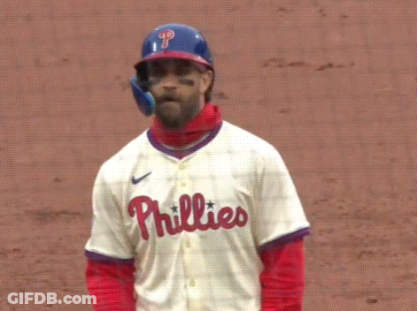 A Baseball Player Wearing A Helmet And A Phillies Jersey Is Standing On A Field . GIF