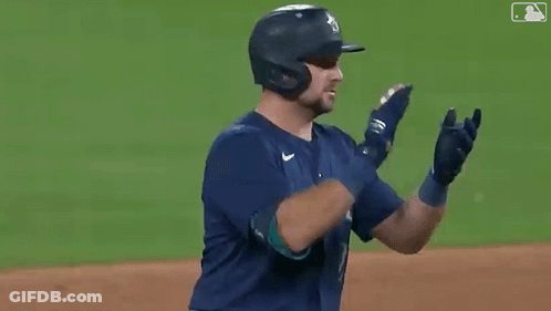 A Baseball Player Wearing A Helmet And Gloves Is Clapping His Hands On The Field . GIF