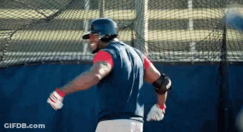 A Baseball Player Wearing A Helmet And Gloves Is Swinging His Bat GIF