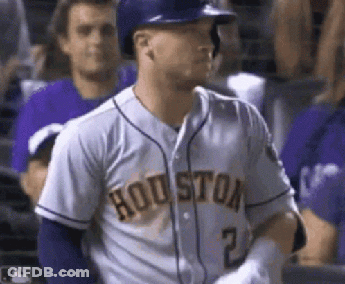 A Baseball Player Wearing A Houston Jersey And A Helmet Is Standing In The Dugout . GIF