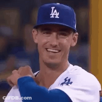 A Baseball Player Wearing A La Hat Is Smiling While Standing On The Field . GIF