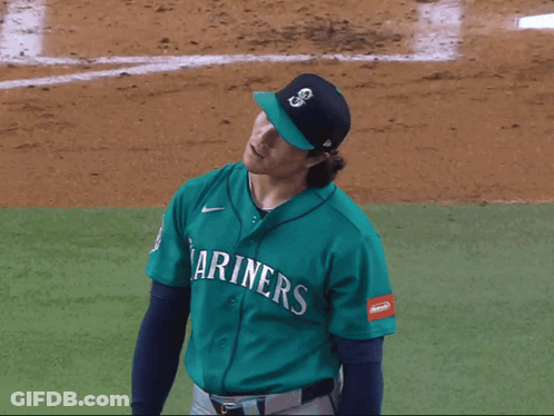 A Baseball Player Wearing A Mariner 'S Jersey Holds His Arms In The Air GIF