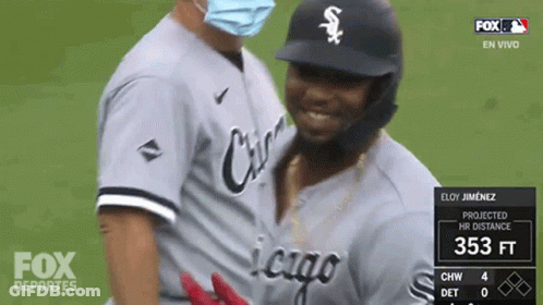 A Baseball Player Wearing A Mask Is Being Hugged By Another Player GIF