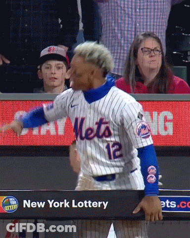 A Baseball Player Wearing A Mets Jersey Is Standing In Front Of A New York Lottery Sign GIF