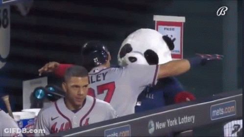 A Baseball Player Wearing A Number 27 Jersey Is Being Hugged By A Panda Mascot GIF